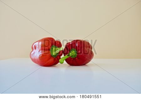 Two red bell peppers on the white table