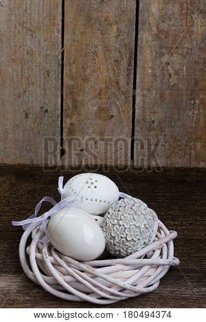 Easter eggs hunt - white eggs in nest on wooden background with copy space