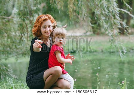 mom and little daughter walking in green summer park