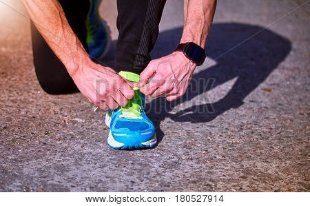 Athlete during training tying shoelaces on sneakers summer.