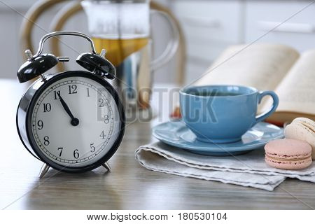 Retro alarm clock showing five minutes to eleven on lunch table