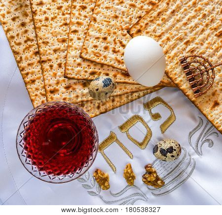 Jewish Passover celebration concept with glass of red wine, walnut, unleavened bread (matzoth) and napkin with Hebrew letters - pesah