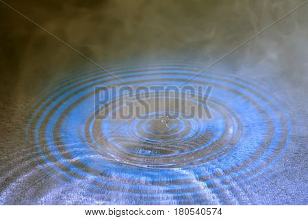 stiffened water drop falling on a water surface ,In smoke with reflection