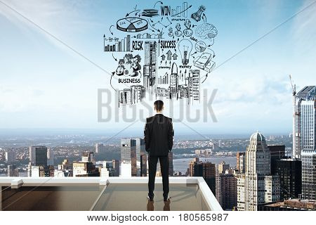 Back view of thoughtful businessman on roof top with city view and business sketch. Success concept