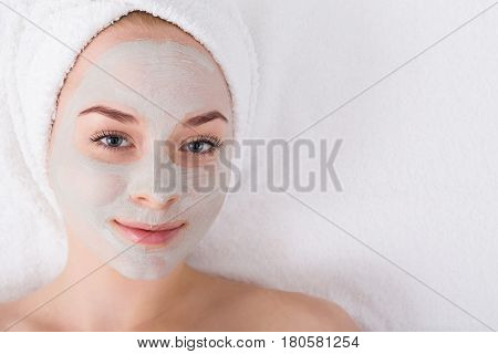 Face mask, spa beauty treatmen with copy space. Woman applying facial clay mask at spa salon, skincare, top view, overhead