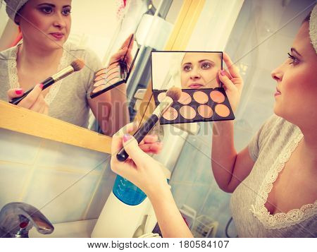 Woman In Bathroom Applying Contour Bronzer On Brush
