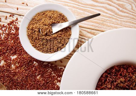 Red wild rice with sesame gomasio seasoning in a white plate over wooden board