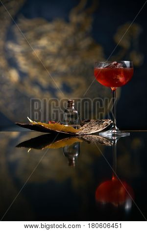 Fresh branded red alcoholic cocktail with a small bottle for alcohol and a red marmalade snack on a black stone bar counter. Concept of alcoholic and non-alcoholic bar beverage.