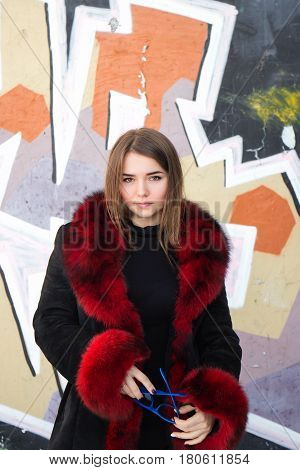 Girl in a black coat with red fur collar.