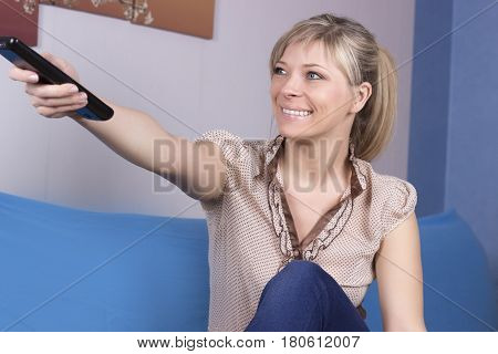 A pretty young girl on the couch switch TV channels.