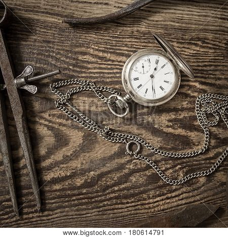 Composition with vintage pocket watch. Old rusty tools and a clock on a dark wooden background. Watch repair