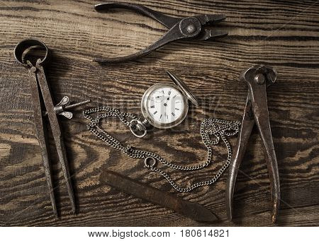 Composition with vintage pocket watch. Old rusty tools and a clock on a dark wooden background. Watch repair