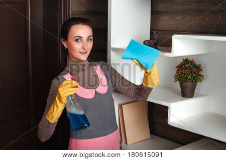 Woman in uniform with rag and cleaning agent