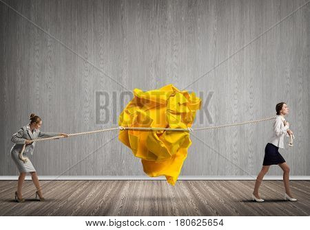 Two businesswomen playing tag of war game