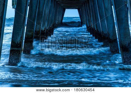 A stormy morning crashes ocean waves against the pier at Tybee Island Georgia.