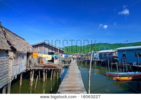 Passerella in legno che conduce in paglia case tetto del villaggio di un'acqua di Tuaran, Malaysia Sabah.