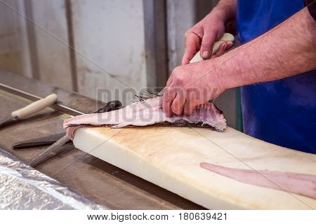 Fish seller short with a thin knife on the market of Cadiz Andalusia Spain