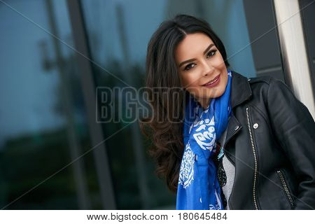 Portrait of Beautiful brunette young oriental beauty female  with black long hair Dressed in Leather jacket and denim pants with Oriental blue scarf and oriental jewelry.