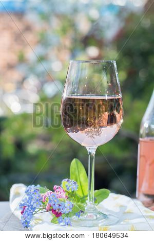 Waiter pouring a glas of cold rose wine outdoor terrase sunny day green garden background