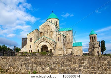 old restored temple of David the Builder Kutaisi 2014. before the temple there is a stone fence and high conifer