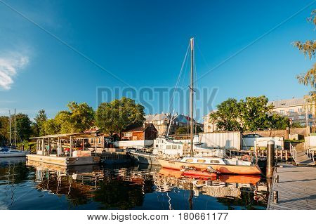 Riga, Latvia - July 1, 2016: Riga, Latvia. Old Yacht Moored At The City Pier Harbour Bay And Quay In Summer Sunny Evening. Reflections From Boats In Water Of Western Dvina River.