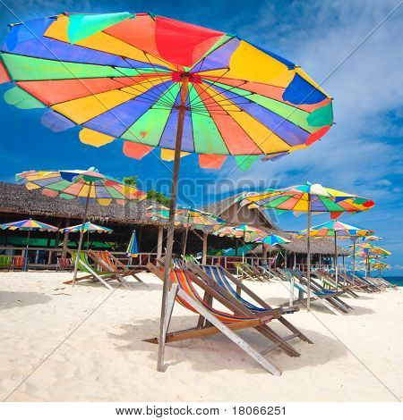 Escapada idílica isla tropical con tumbonas y sombrillas en la playa de arena blanca