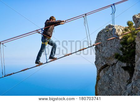 CRIMEA, RUSSIA - MAY 19, 2016: Tourist walking on rope bridge on the Mount Ai-Petri over the sea. Ai-Petri is one of the highest mountains in the Crimea and tourist attraction.