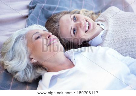 Enjoying peaceful minutes together. Positive delightful mature woman enjoying picnic and lying on the blanket while enjoying weekend with aged mother