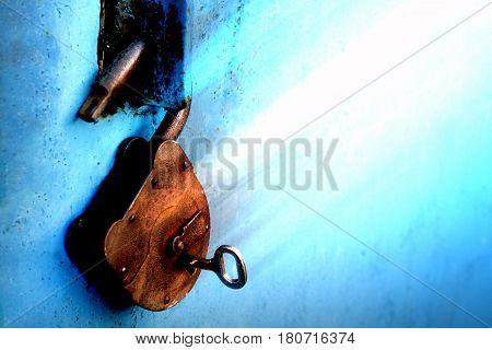 Old rusty lock with a key on a blue background.