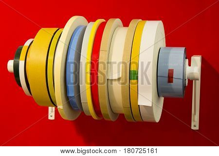 Variety double adhesive tape in; rolls of different types of tape with red background