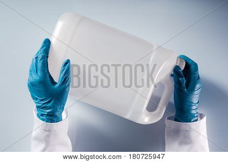 Chemical scientist opening white unlabeled plastic tank canister with chemicals on laboratory table