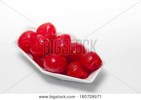 Cherries into a white bowl on white background