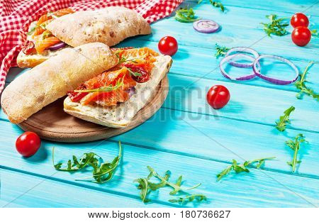 sandwich with smoked salmon on blue wooden table.