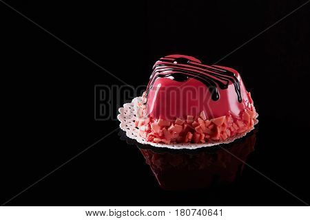 Pink heart shaped frosting cake with chocolate topping and strawberry cracked on black background. Confectionery. Delicious dessert.