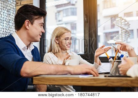 Like this subject. Cheerful lively international students sitting in the cafe and learning genetics while preparing project work
