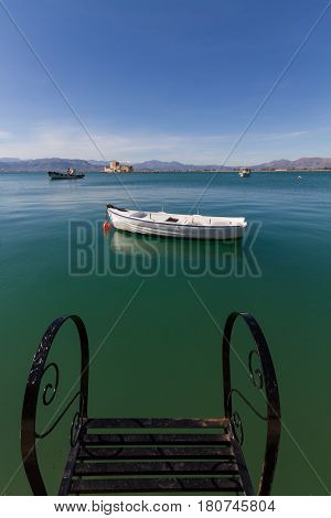 Pier Steps Traditional Fishing Boats and Bourtzi Fortress in the distant background in Nafplion Greece- portrait photo
