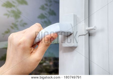 A close-up of the hand turns the handle of the plastic window on which the opening limiter is installed.