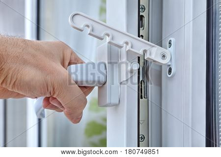 Close-up the hand opens the PVC window by pulling the handle provided with a window limiter.