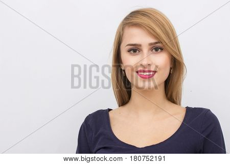 Fashion portrait of a girl posing in bright, spacious studio with a gray background in a stylish comfortable and simple clothes. young girl with clean skin and perfect face