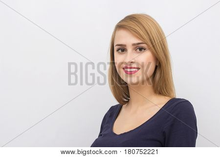 Fashion portrait of a girl posing in bright, spacious studio with a gray background in a stylish comfortable and simple clothes. young girl with clean skin and perfect face