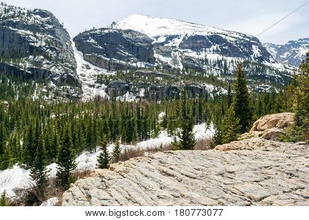 Overlook in the Colorado Rocky Mountains with a wide background of snow covered peaks and evergreen forest