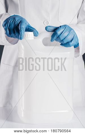Chemical scientist opening white unlabeled plastic tank canister with chemicals on laboratory table