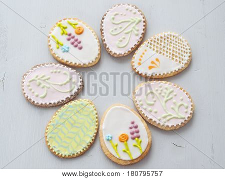 Easter egg shaped gingerbread glazed with royal icing. Homemade gift cookie upon wooden table. Easter treat. Food background. Selective focus on the front.