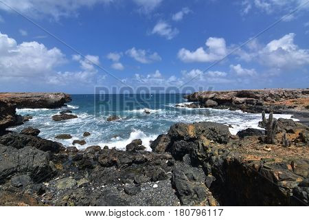Rugged lava rocks encircling the cove of Aruba's black sand stone beach.