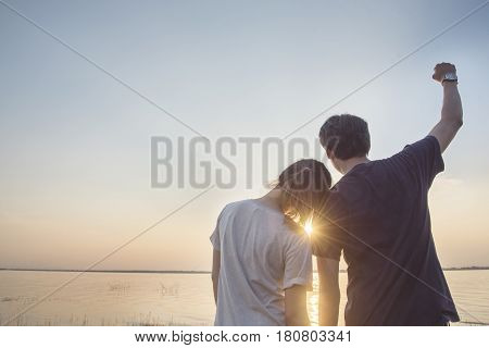 Romantic young asian couple in love sitting on pier during sunset time