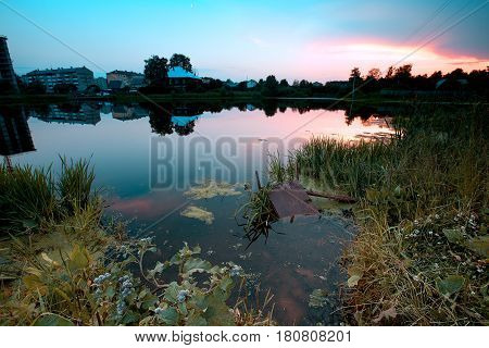 A small dirty city swamp at sunset.