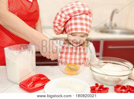Little girl and grandmother stirrring cookie dough in the kitchen