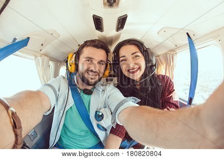 Happy smiling couple making selfie with smartphone inside plane cabin during flight. Young man and woman enjoying trip