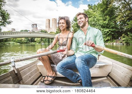 Happy couple having fun on a boat in Central Park - Interracial couple of tourists sighseeing Manhattan
