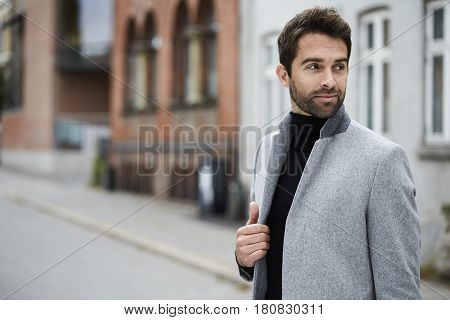 Smiling guy in grey overcoat looking away